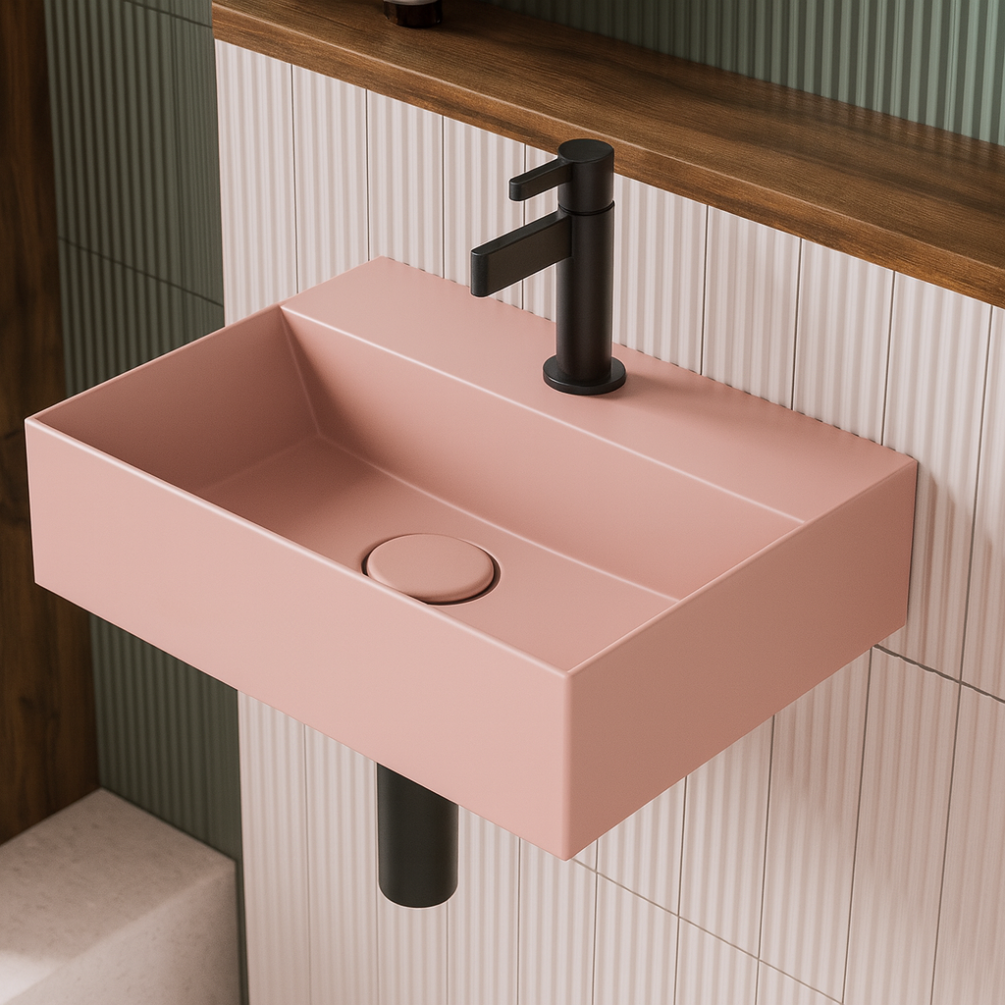 Lifestyle image of the Zero 3 400mm x 300mm Matt Pink Cloakroom Wall Hung Basin attached to tiled walls, with a black basin mixer tap